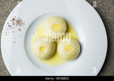 Three potato dumplings with butter on a plate Stock Photo