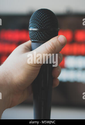 Man hand with karaoke microphone in front of TV. Stock Photo