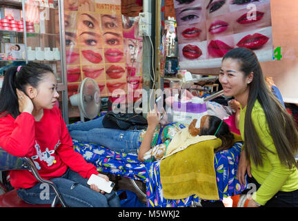 Street beauty therapist doing a facial for a customer, example of Cambodia culture;  Phnom Penh, Cambodia, Asia Stock Photo