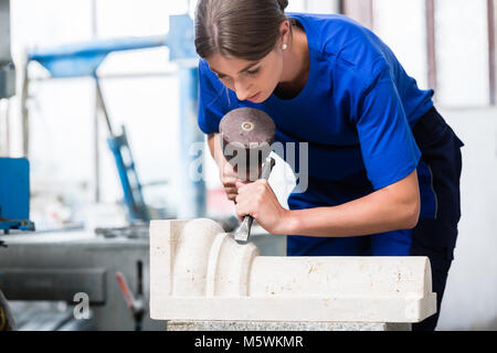 woman Stonemason carving pillar out of stone in workshop Stock Photo