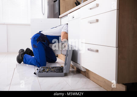 Plumber In Overall Fixing Sink Pipe In Kitchen Stock Photo