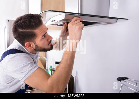 Close-up Of A Young Male Electrician Repairing Kitchen Extractor Filter Stock Photo
