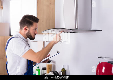 Male Electrician With Clipboard Repairing Kitchen Extractor Filter Stock Photo