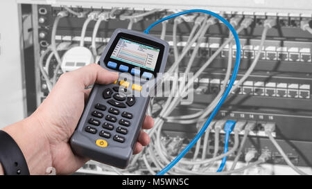 Measurement a cables connected in patch panels of rack case. Detail of male hand when testing structured cabling by qualified cable performance tester. Stock Photo