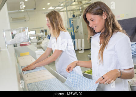 laundry worker folding towels at dry cleaners Stock Photo