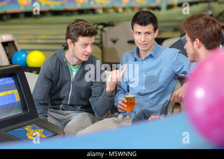 Three friends in bowling alley, chatting Stock Photo