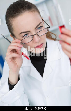 seriously looking female doctor with blood probe and request form Stock Photo