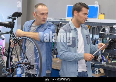 two bicycle repairer colleagues working in bike garage Stock Photo
