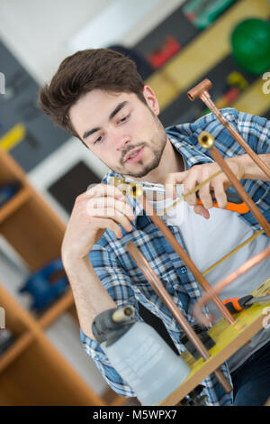 young plumber worker cuts the tube Stock Photo