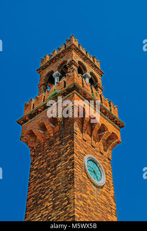 Detail of clock tower made of bricks with sunny blue sky in the background at Murano, a small and pleasant town on top of islands near Venice. Stock Photo