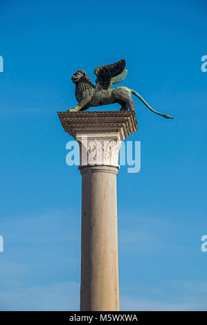Close-up of column with the winged lion, symbol of Venice, and blue sunny sky in Piazza San Marco at Venice, the historic and amazing marine city. Stock Photo