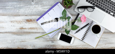Office desktop with laptop, calendar, coffee and pink rose on white rustic desk Stock Photo