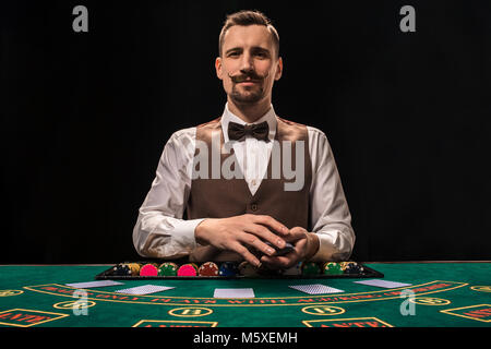 Croupier behind gambling table in a casino. Stock Photo