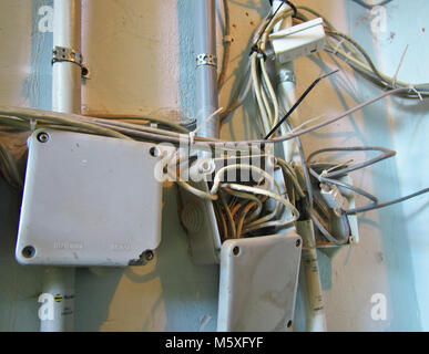 Randomly arranged in the communication network wires in boxes on the wall Stock Photo
