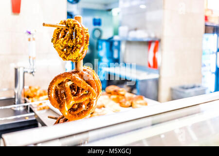 Hanging baked orange bread large pretzels inside bakery shop store in New York City, NYC Stock Photo