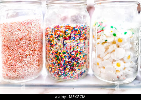 Closeup of jars of sweet colorful sprinkles and toppings decorations for ice cream, desserts on display in glass, store shop bakery Stock Photo