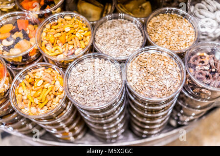 Many packaged seeds, nuts, dried fruit in plastic containers on display on store shop shelves, sunflower seeds mix, pretzels Stock Photo