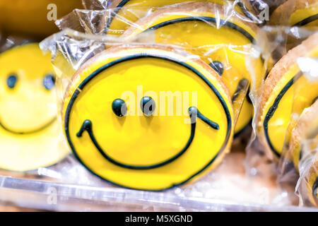 Macro closeup of plastic wrapped smiley smile yellow cookies decorated piping frosting icing in bakery store shop Stock Photo