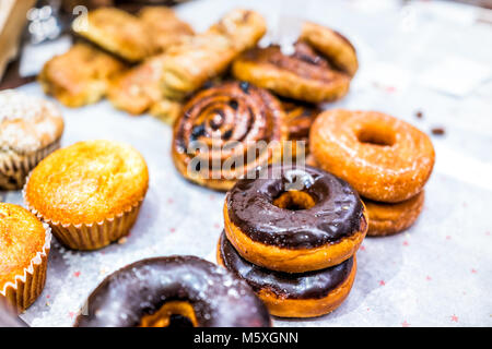 Many different selection of pastry dessert sweets for continental breakfast, chocolate fried donuts, muffins, cinnamon rolls buns on paper tray in caf Stock Photo