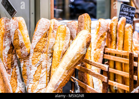 Closeup of fresh golden traditional standard, ficelle many baked baguette loaves in bakery basket wooden by window, sign, price Stock Photo