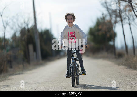 Little girl going with her bike towards the camera smiling. Horizontal shot with natural light Stock Photo