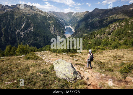 Hiker on the hiking trail from Alpe Corte del Sasso to Alpe Corte di Mezzo, in the back Sambuco, Lago di Sambuco, Fusio Stock Photo