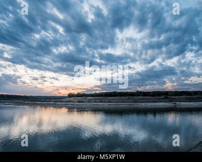 Sunset Behind Small Hill with Storm Clouds in the Sky Stock Photo