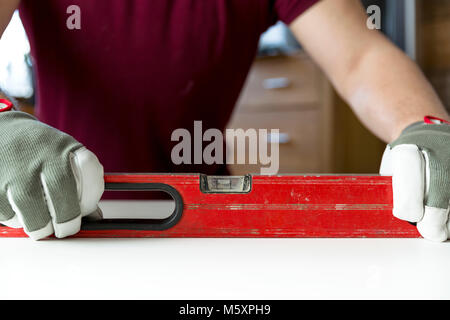 Carpenter's hands checking level of wooden table at home. DIY projects, handyman Stock Photo
