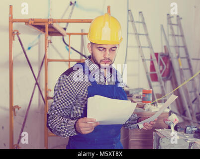 Diligent serious  builder is looking on the project of work for the object. Stock Photo