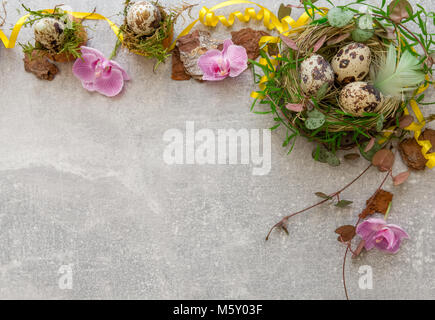 Floral background of quail eggs in the nest, spring grass and flowers, ribbons, feathers, natural materials. Flat lay, top view. Easter concept. Stock Photo