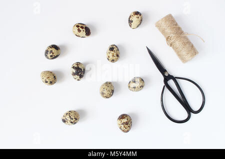 Easter, spring greeting card, invitation with quail eggs, black scissors and natural rope on white table. Feminine styled stock flat lay photo, top view. Stock Photo