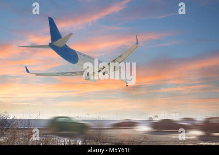 Tail view of landing airplane. Aircraft flying over highway.  Road with high traffic near airport runway. Type of transport comparison.  Travel concept Stock Photo