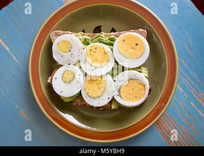 Sliced hard boiled eggs on toast with avocado. Stock Photo