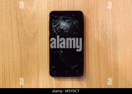 Smartphone mobile with a broken screen. Background wood Stock Photo