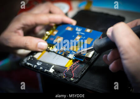 Hands holding a soldering iron close-up. Mobile phone repair and tablet Stock Photo