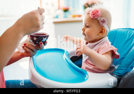 Portrait Of Happy Young Baby In High Chair being fed Stock Photo