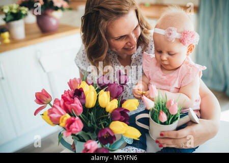 Child daughter congratulates moms and gives her flowers Stock Photo