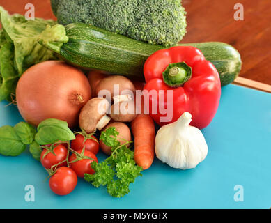 Fresh raw vegetables on a cutting board. arrangement of red bell pepper, zucchini, broccoli, salad, onion, carrots and garlic, decorated on bamboo. Stock Photo