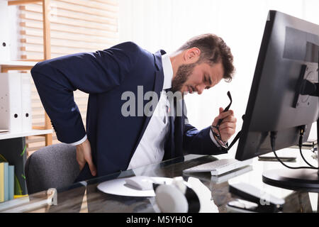 Young Businessman Suffering From Backache At Workplace Stock Photo