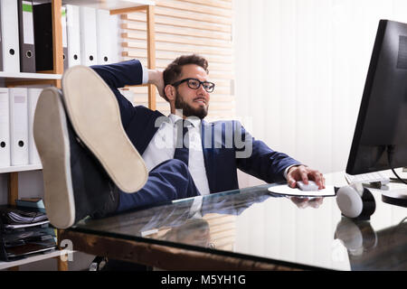 Relaxed Young Businessman Working On Computer At Workplace Stock Photo