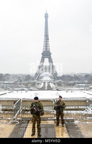 As part of the Vigipirate plan, two french soldiers patrol with assault rifle on the Trocadero esplanade, opposite the Eiffel tower, on a snowy day. Stock Photo