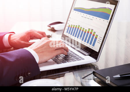 Close-up Of A Businessperson's Hand Analyzing Graph On Laptop In Office Stock Photo