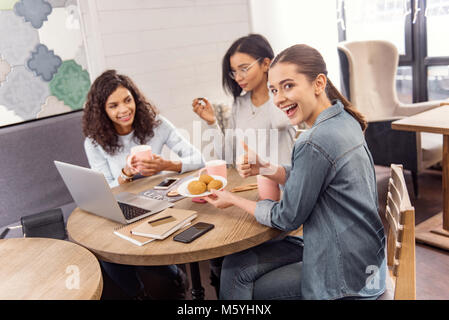 Joyful three students taking little bite Stock Photo