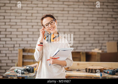 hardworking professional female worker with pen and tablet in workshop Stock Photo