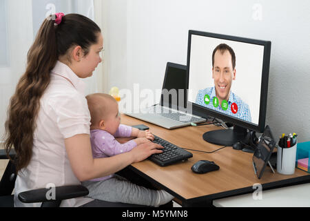 Woman Video Conferencing With Male Friend On Computer At Home Stock Photo