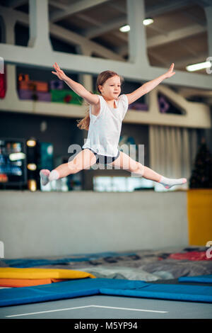 Girl jumping high in striped tights on trampoline. Stock Photo