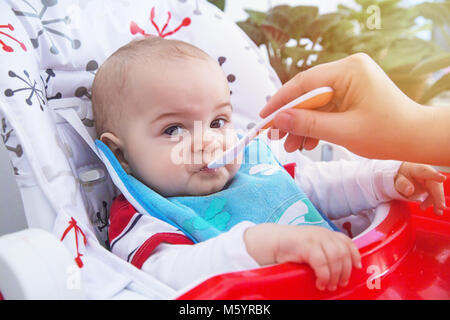 Pouting baby have lunch at the table in a suny day. Stock Photo