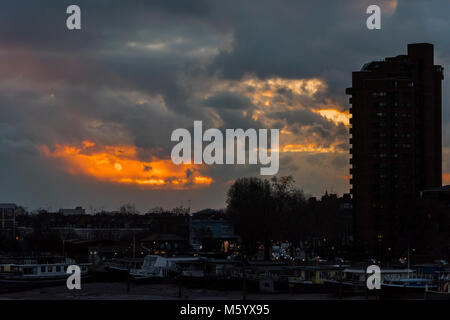 Sun sets over flats and houseboats in teh Chelsea Wharf area, as seen from Battersea Bridge, london. Stock Photo