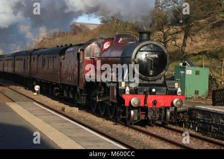 Preserved steam locomotive 45699 Galatea heading through Garsdale station on the Settle to Carlisle railway line with the Cumbrian Mountain Express. Stock Photo