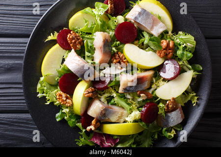 Fresh mackerel salad with apples, walnuts, beets and mix lettuce close-up on a plate on the table. horizontal top view from above Stock Photo